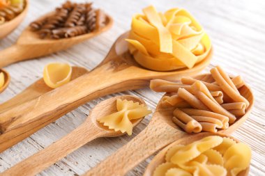 Tahta kaşıklar ışık arka plan üzerinde pişmemiş makarna ile