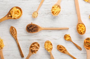 Tahta kaşıklar ışık arka plan üzerinde pişmemiş makarna ile