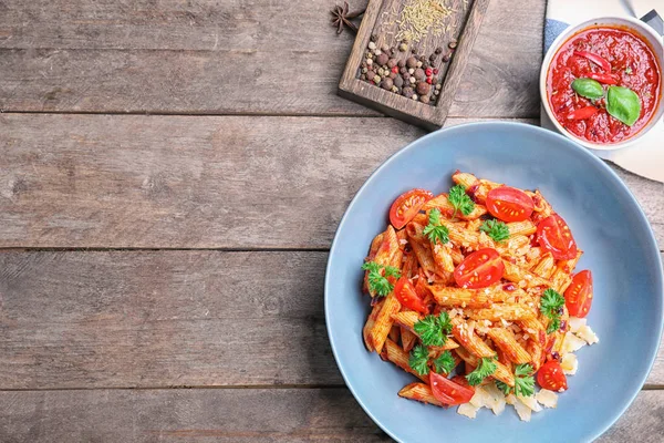 Plate with delicious penne pasta and garnish on table — Stock Photo, Image