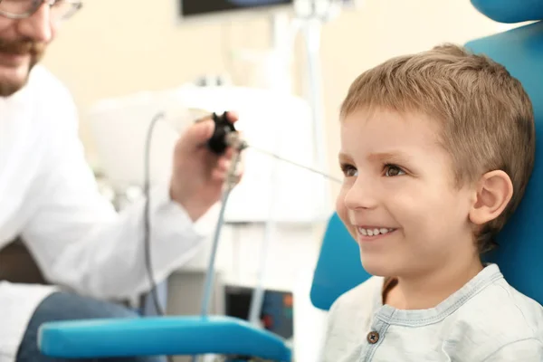 Отоларинголог осматривает ухо маленького мальчика с помощью ЛОР-телескопа в больнице — стоковое фото