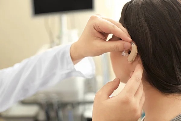 Otorrinolaringólogo poniendo audífono en el oído de la mujer en el interior — Foto de Stock
