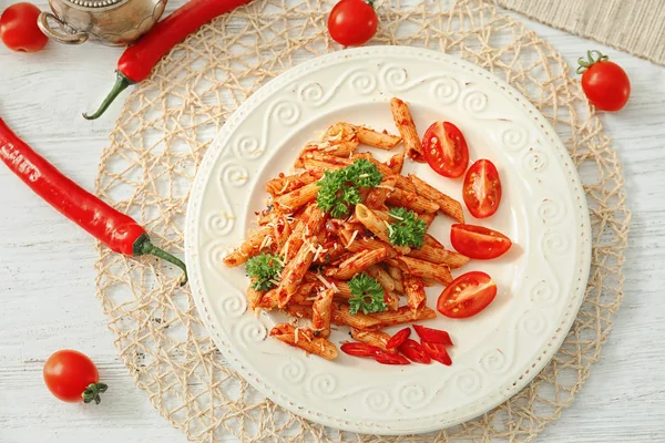 Plate of tasty penne pasta with tomato sauce on table — Stock Photo, Image