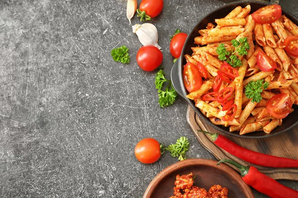 Samenstelling met smakelijke penne pasta op grijze achtergrond — Stockfoto