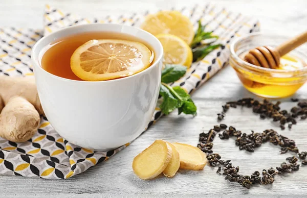Чашка вкусного чая с лимоном, имбирем и медом на столе — стоковое фото