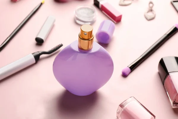 Bottle of perfume with decorative cosmetics and brushes on color background — Stock Photo, Image