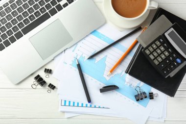 Laptop, fincan kahve ve kırtasiye, düz ahşap arka plan üzerinde yatıyordu. Çalışma alanı tablosu kompozisyon