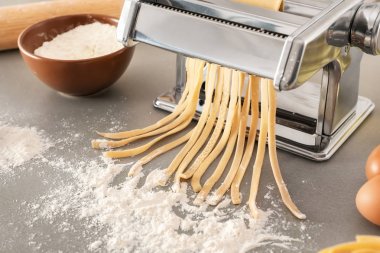 Mutfak masasının üzerinde hamur ile metal makarna üreticisi