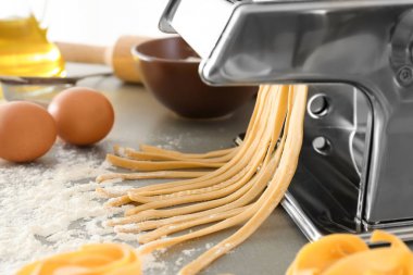 Mutfak masasının üzerinde hamur ile metal makarna üreticisi