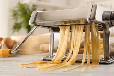 Mutfak masasının üzerinde hamur ile metal makarna üreticisi