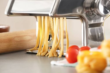 Mutfak masasının üzerinde hamur ile metal makarna üreticisi