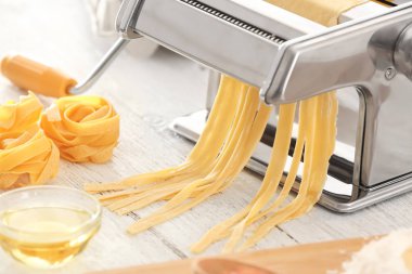 Mutfak masasının üzerinde hamur ile metal makarna üreticisi