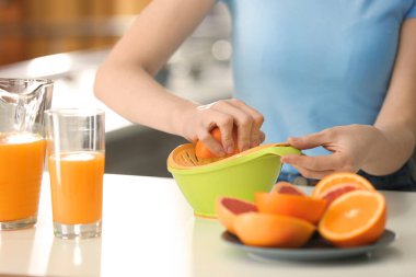 Genç kadın mutfakta narenciye suyu sıkma