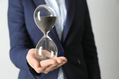 Kadın holding kum kum saati gri arka plan üzerinde. Zaman yönetimi kavramı