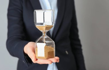 Kadın holding kum kum saati gri arka plan üzerinde. Zaman yönetimi kavramı