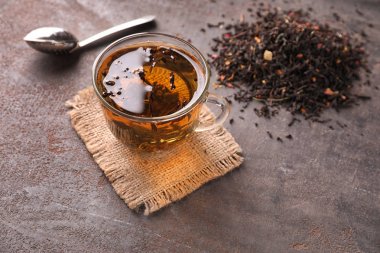 Sıcak içecek ve kuru çay yaprakları gri arka plan üzerinde