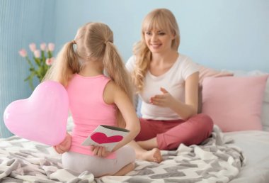 Küçük kız gizleme el yapımı kart ve balon anne arkasında yatak odasında geri