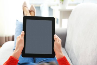 Evde tablet bilgisayar kullanan genç bir kadın.