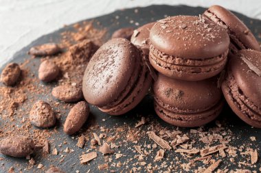 Lezzetli çikolata macarons ve kakao çekirdekleri, closeup ile kayrak plaka
