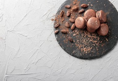 Lezzetli çikolata macarons ve gri arka plan, üstten görünüm üzerine kakao çekirdekleri ile kayrak plaka