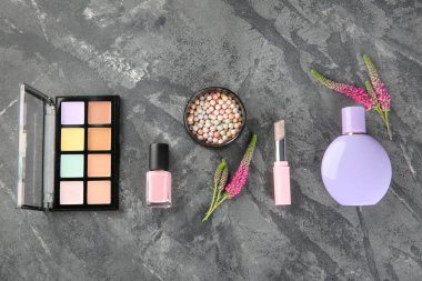 Gri arkaplanda kozmetik ürünlerle düz kompozisyon