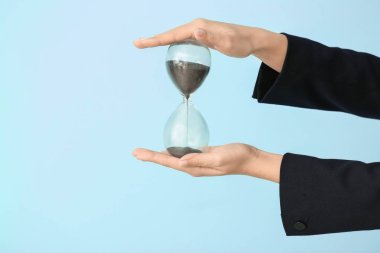 Renk arka plan üzerinde kum saati tutan kadın. Zaman yönetimi kavramı