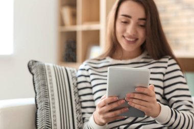 Genç kadın evde koltukta istirahat ederken tablet kullanma