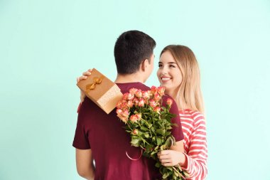 Hediye kutusu ve onun erkek arkadaşı renk arka plan üzerinde kucaklayan çiçekler olan mutlu kadın