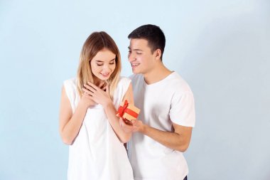 Renk arka plan üzerinde sevgili kız arkadaşına hediye veren genç adam