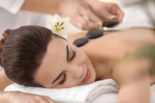 Jovem mulher desfrutando de massagem de pedra no salão de spa — Fotografia de Stock