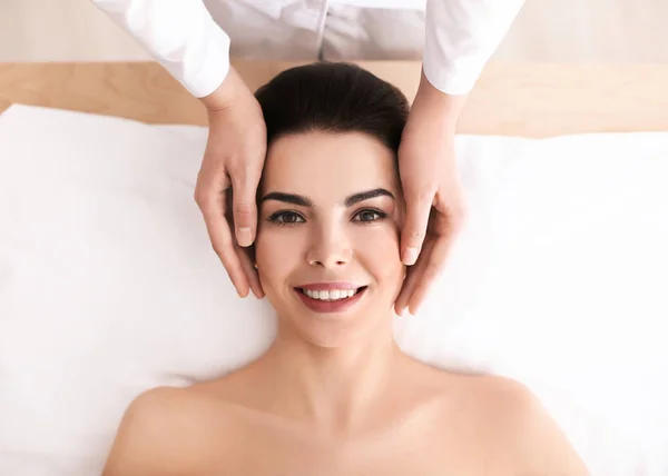 Молода жінка насолоджується масажем обличчя в спа-салоні — стокове фото
