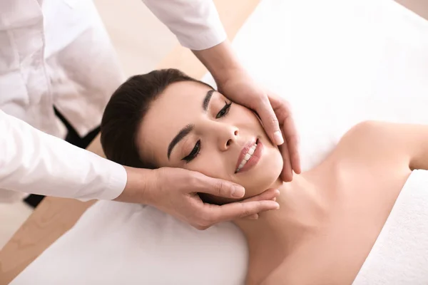 Mujer joven disfrutando de masajes faciales en el salón de spa —  Fotos de Stock