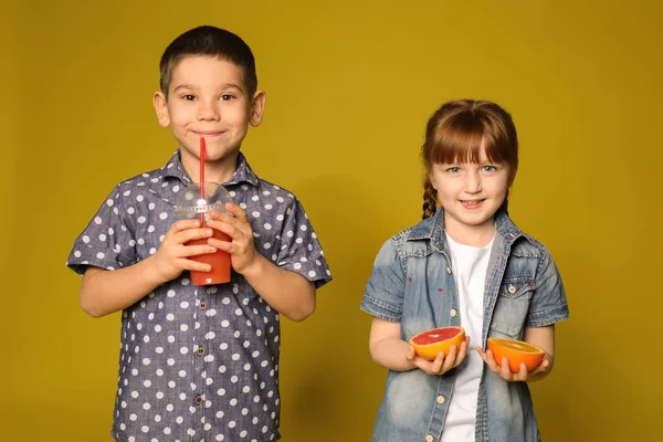 Słodkie dzieci z owoców cytrusowych i soku na kolor tła — Zdjęcie stockowe