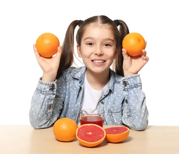 Vicces kis lány, citrus gyümölcs és gyümölcslé asztalnál fehér háttér — Stock Fotó