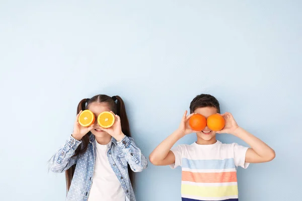 Funny little children with citrus fruit on color background — Stock Photo, Image