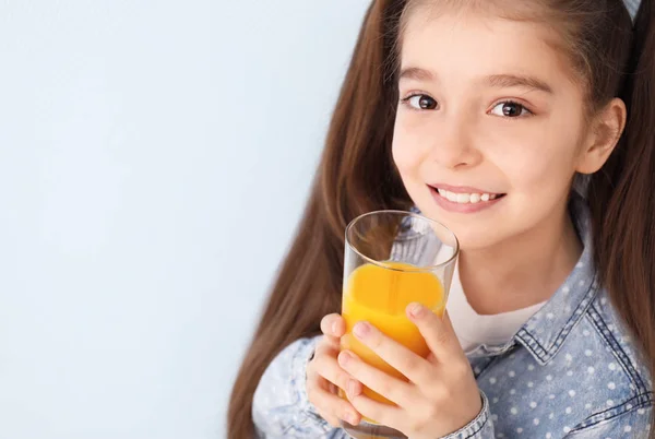 Engraçado menina bebendo suco de citrinos no fundo de cor — Fotografia de Stock