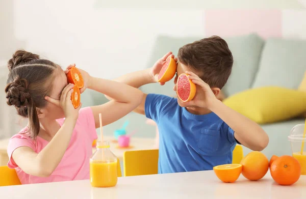 Funny little children with citrus fruit and juice at home — Stock Photo, Image