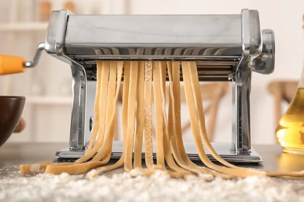 Metal pasta maker with dough on kitchen table — Stock Photo, Image