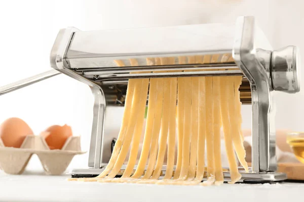 Metal pasta maker with dough on kitchen table — Stock Photo, Image