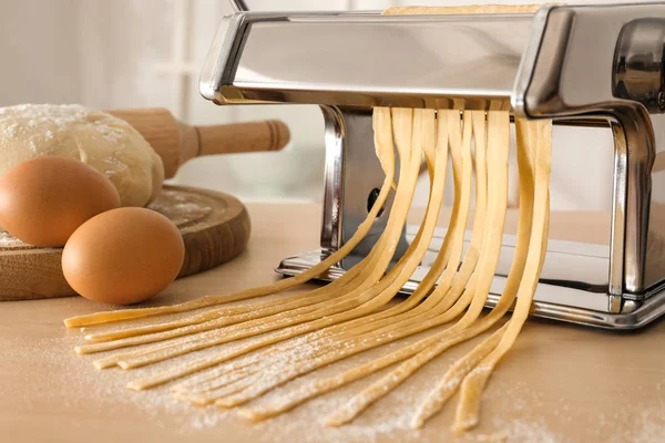 Metal pasta maker with dough on kitchen table — Stock Photo, Image