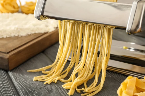 Metal pasta maker with dough on kitchen table — Stock Photo, Image