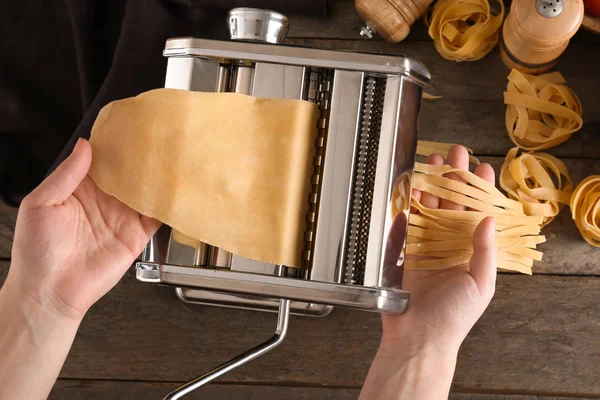 Woman making noodles with pasta machine at table, top view — Stock Photo, Image