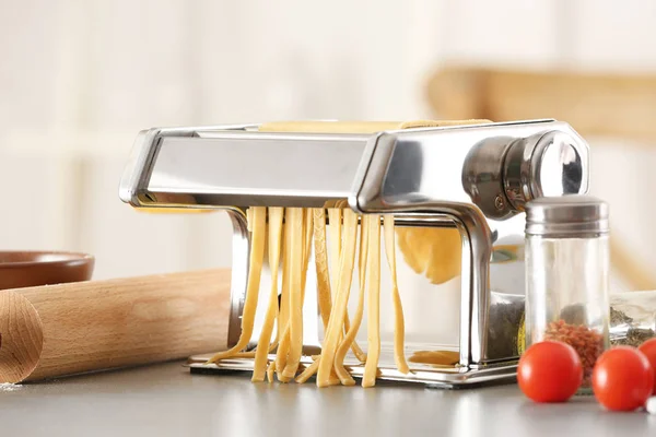 Pembuat pasta logam dengan adonan di atas meja dapur — Stok Foto
