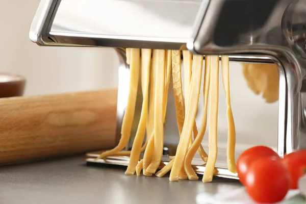 Nudelmaschine aus Metall mit Teig auf Küchentisch — Stockfoto