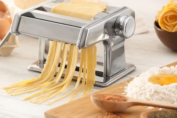 Metal pasta maker with dough on kitchen table — Stock Photo, Image