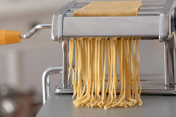 Metalen Pastamachine met deeg op tafel tegen onscherpe achtergrond — Stockfoto