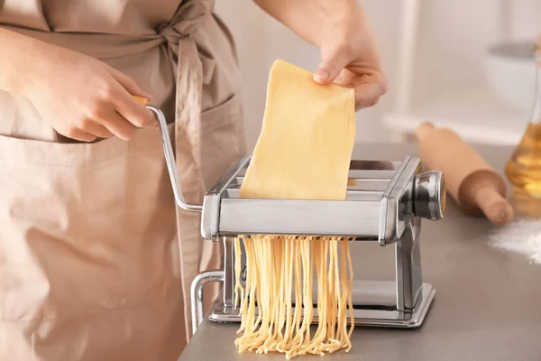 Vrouw maakt noedels met pasta machine aan tafel — Stockfoto