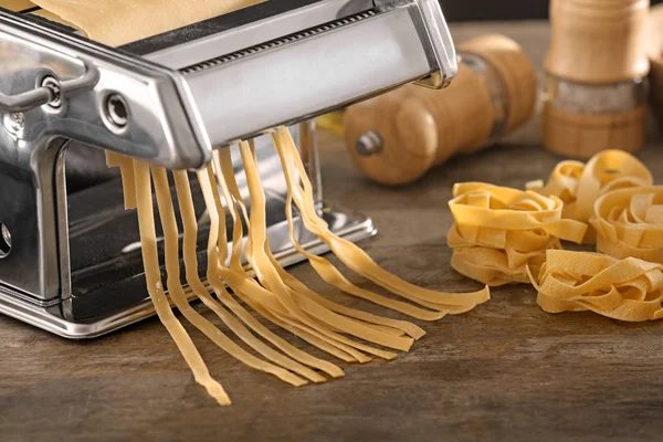 Nudelmaschine aus Metall mit Teig auf Küchentisch — Stockfoto