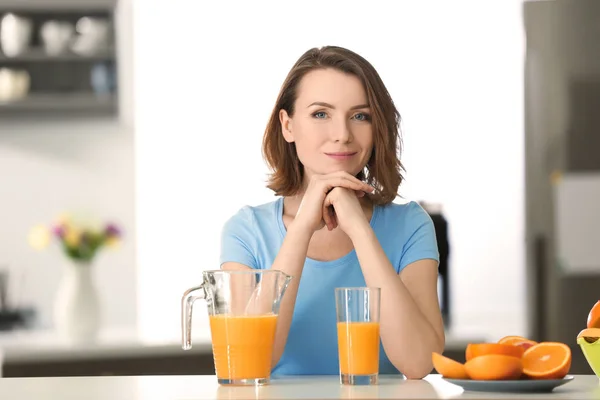 Belle jeune femme avec des agrumes et du jus dans la cuisine — Photo