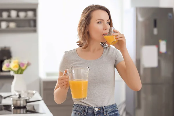 Beautiful woman drinking citrus juice in kitchen — Stock Photo, Image