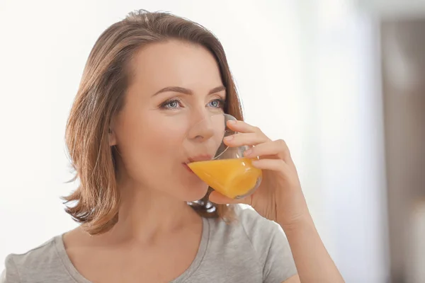 Mooie vrouw, drinken van SAP van citrusvruchten op lichte achtergrond — Stockfoto